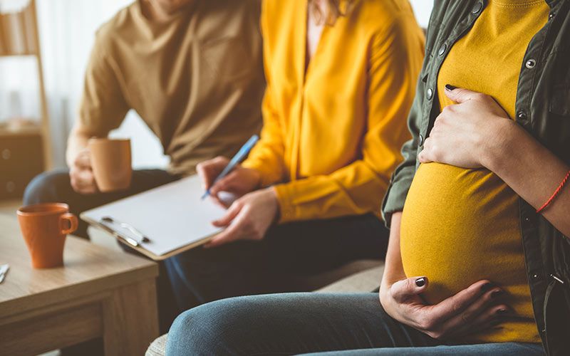 Couple with pregnant woman holding stomach