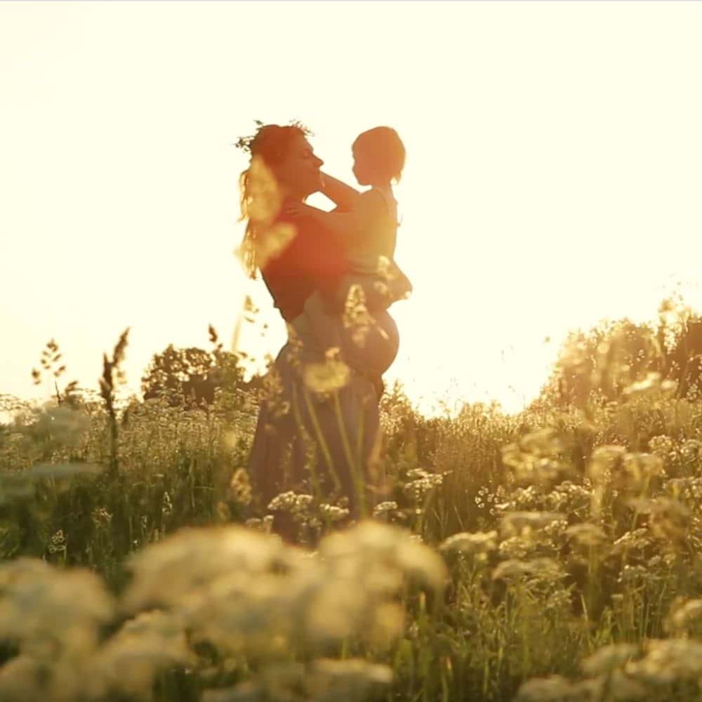 Mother and child in a field of flowers at sunset